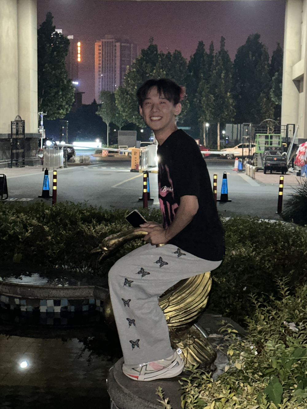 陈明远在夜色里坐在金色的牛形雕塑上笑着看向镜头